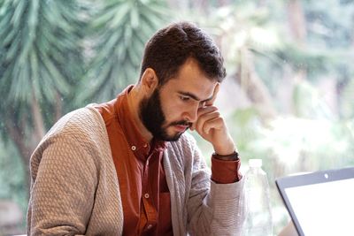 Young man looking away while sitting on table