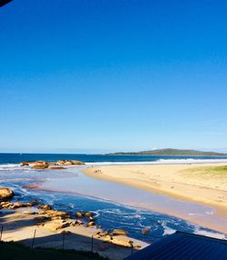 Scenic view of beach against clear blue sky