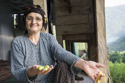 Portrait of woman holding fruits at home