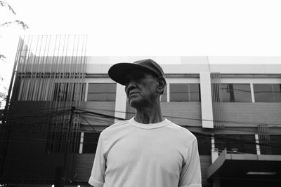 Young man looking at building against sky