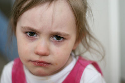 Close-up portrait of cute sad girl at home