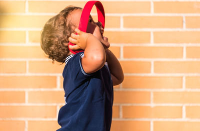 Portrait child listening to music with headphones on brick wall