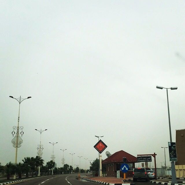 transportation, car, road, street light, land vehicle, mode of transport, clear sky, street, the way forward, road marking, copy space, built structure, sky, on the move, architecture, diminishing perspective, building exterior, outdoors, in a row, road sign