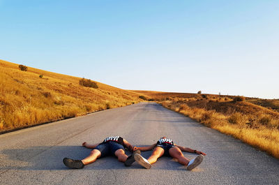 Woman lying on road against clear sky