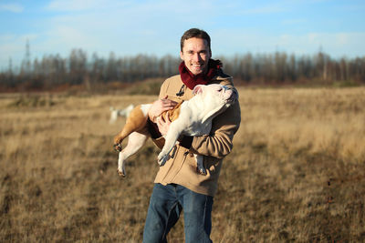 Portrait of smiling young man with dog standing on grass