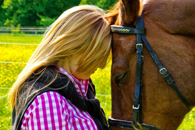 Side view of woman standing by horse on field