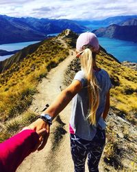 Rear view of friends standing on mountain against sky