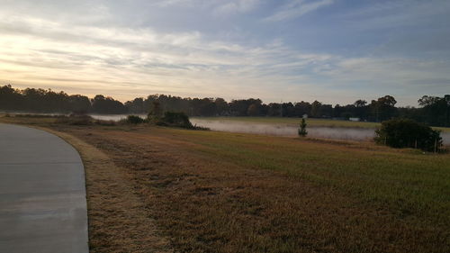 Scenic view of farm against sky during sunset