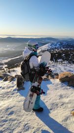 Man carrying snowboard while standing outdoors