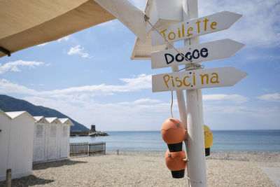 Information sign on beach against sky