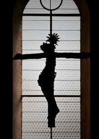 Close-up of silhouette statue against window in church