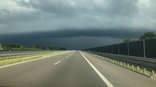 Empty road against cloudy sky