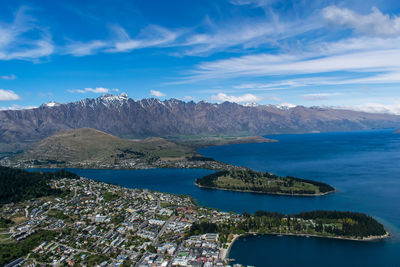 Aerial view of sea and mountains against blue sky