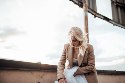 Young woman looking at camera against sky