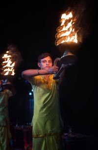 Portrait of man holding lit diya at night