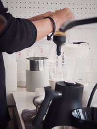 Midsection of woman making coffee in kitchen