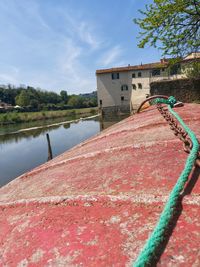 Close-up of red building by lake against sky