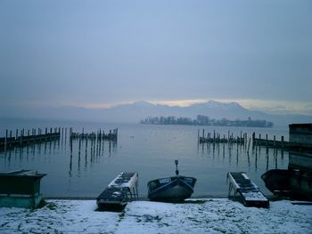 Boats moored on lake against sky during sunset