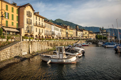 Sailboats moored on canal by buildings in city against sky