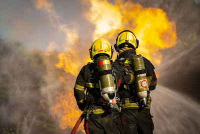 Rear view of people on fire against clouds