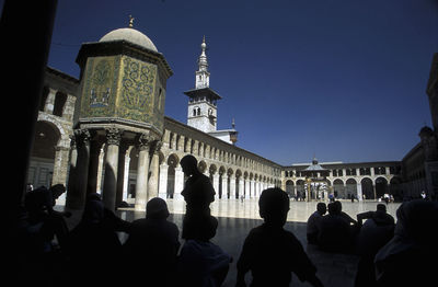 People sitting at umayyad mosque against clear sky