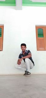 Portrait of young man standing against wall