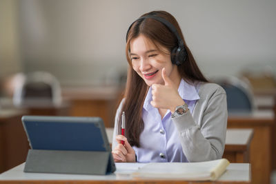 Young woman using phone while sitting on table