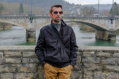 Man standing on bridge over river