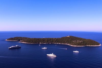 Boats sailing in sea against clear blue sky