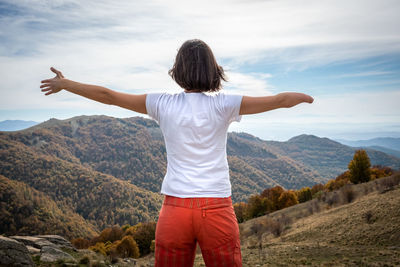 Rear view of man standing on mountain against sky