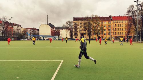 People playing soccer on field against sky