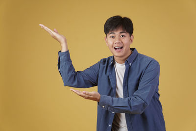 Portrait of smiling man standing against yellow background