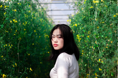 Portrait of woman standing against plants