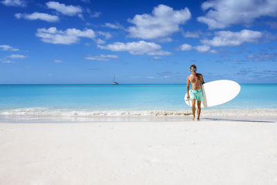 Rear view of woman standing at beach against sky