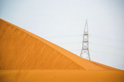 Low angle view of electricity pylon against clear sky