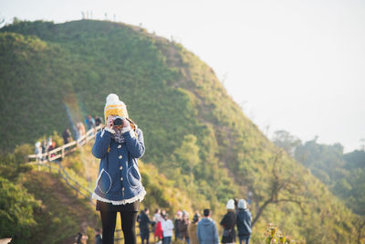Woman photographing while standing on mountain