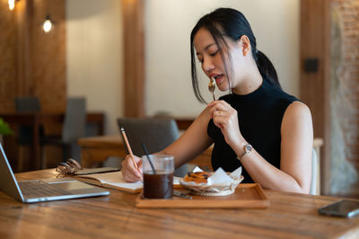 Young woman using mobile phone at table