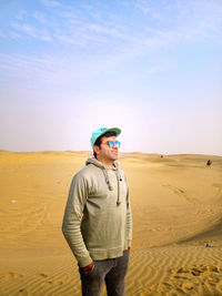 Man standing on sand at beach against sky