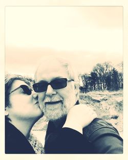 Portrait of young couple with sunglasses against clear sky