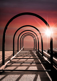 View of metal bridge over sea against sky during sunset