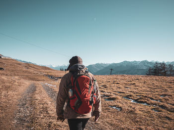 Rear view of man standing on mountain against clear sky