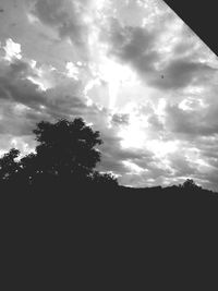 Silhouette of trees against cloudy sky