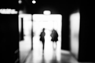 Defocused image of people walking on illuminated corridor