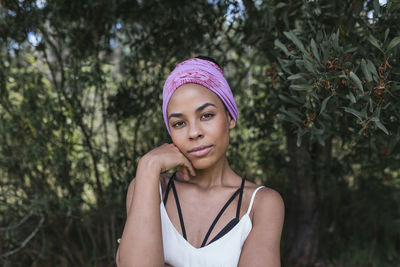 Portrait of beautiful young woman against plants