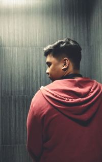 Boy looking away while standing against wall