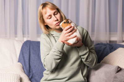 Young woman using phone while sitting on bed at home