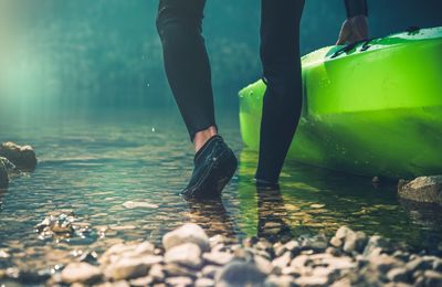 Low section of man walking by kayak