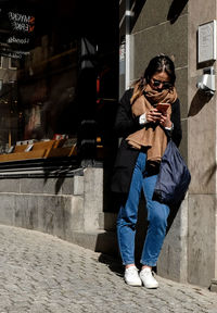 Full length of man using mobile phone on street