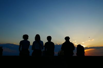 Silhouette people looking at sunset sky