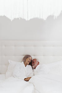 Happy romantic senior couple on bed in hotel room